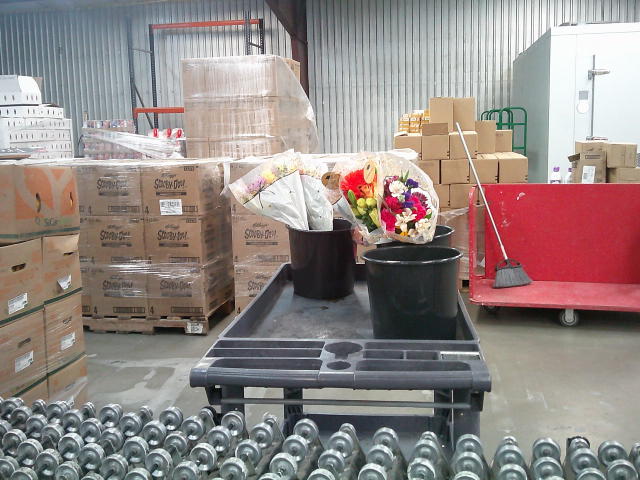 Flower bouquets in buckets on a shelf cart.